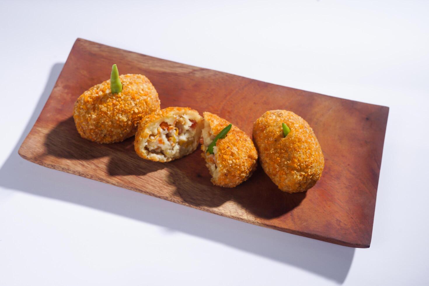 Delicious Indonesian snack named Risol or Risoles filled with smoked beef mayonnaise and crispy fried bread crumb texture on a wooden plate, isolated on a white background photo