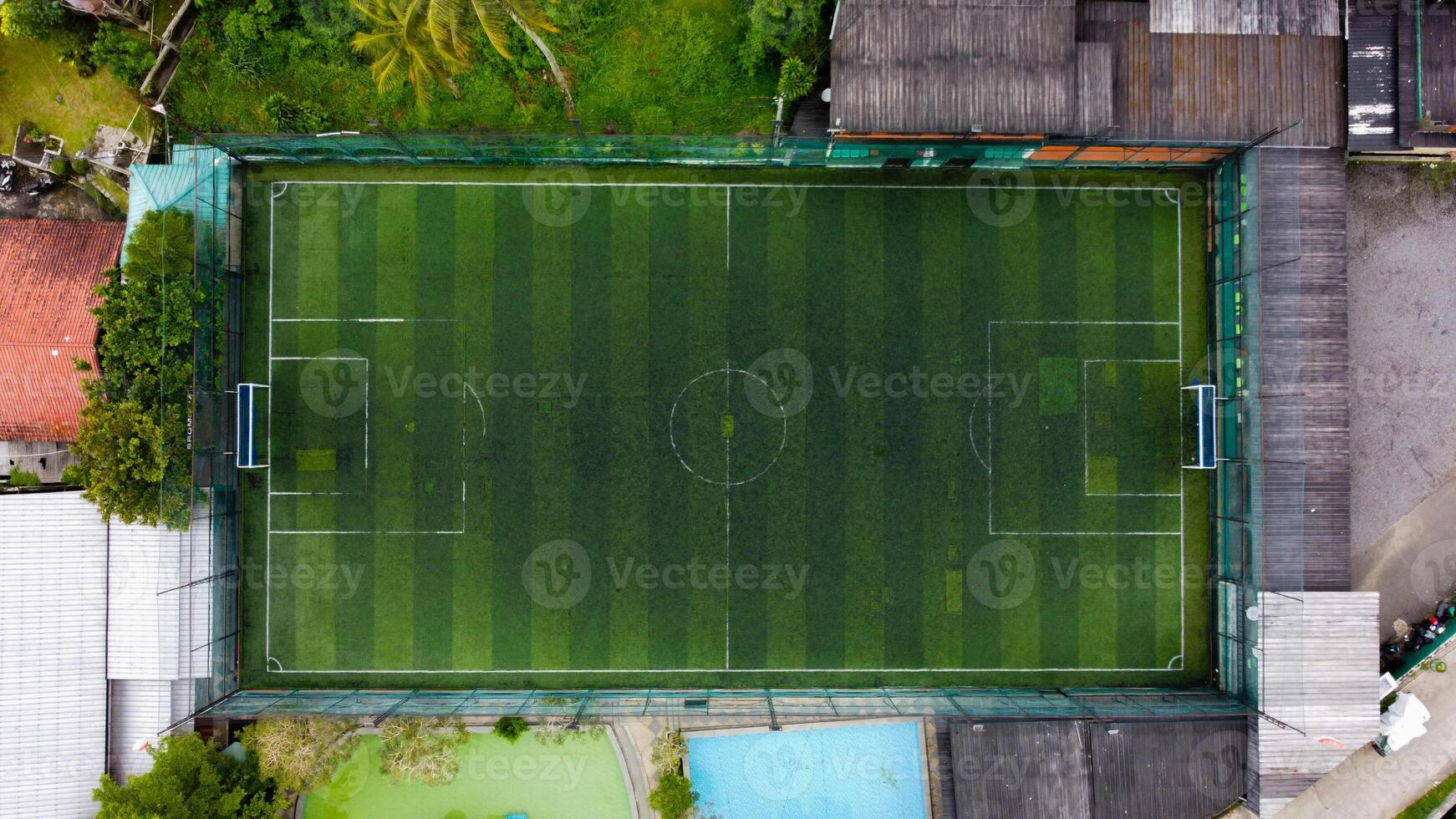 Football field seen from drone with palm trees and building people, Aerial view of soccer field, sport and soccer game concept, Mini Soccer photo