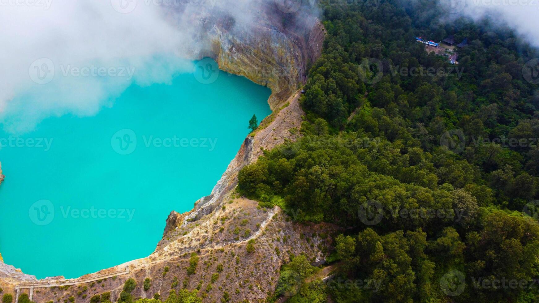 Experience the mesmerizing of Kelimutu's Three Color Lake in Ende. Wrapped in mystical clouds, this magical site, rich in legend, offers a breathtaking landscape that captivates the soul. photo