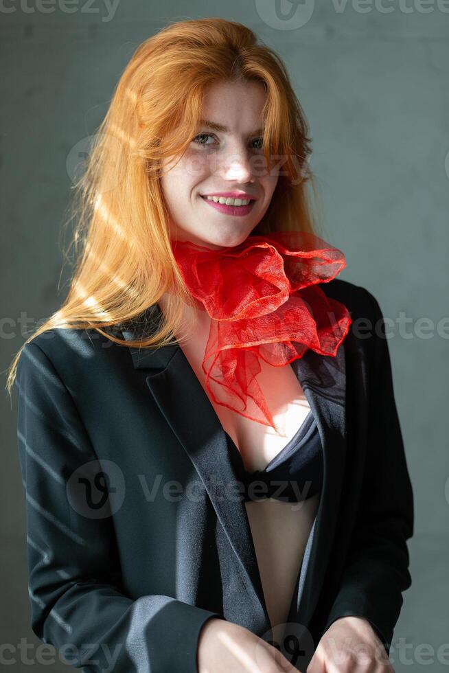 Portrait of a red-haired girl with a red scarf around her neck, in a suit and top photo