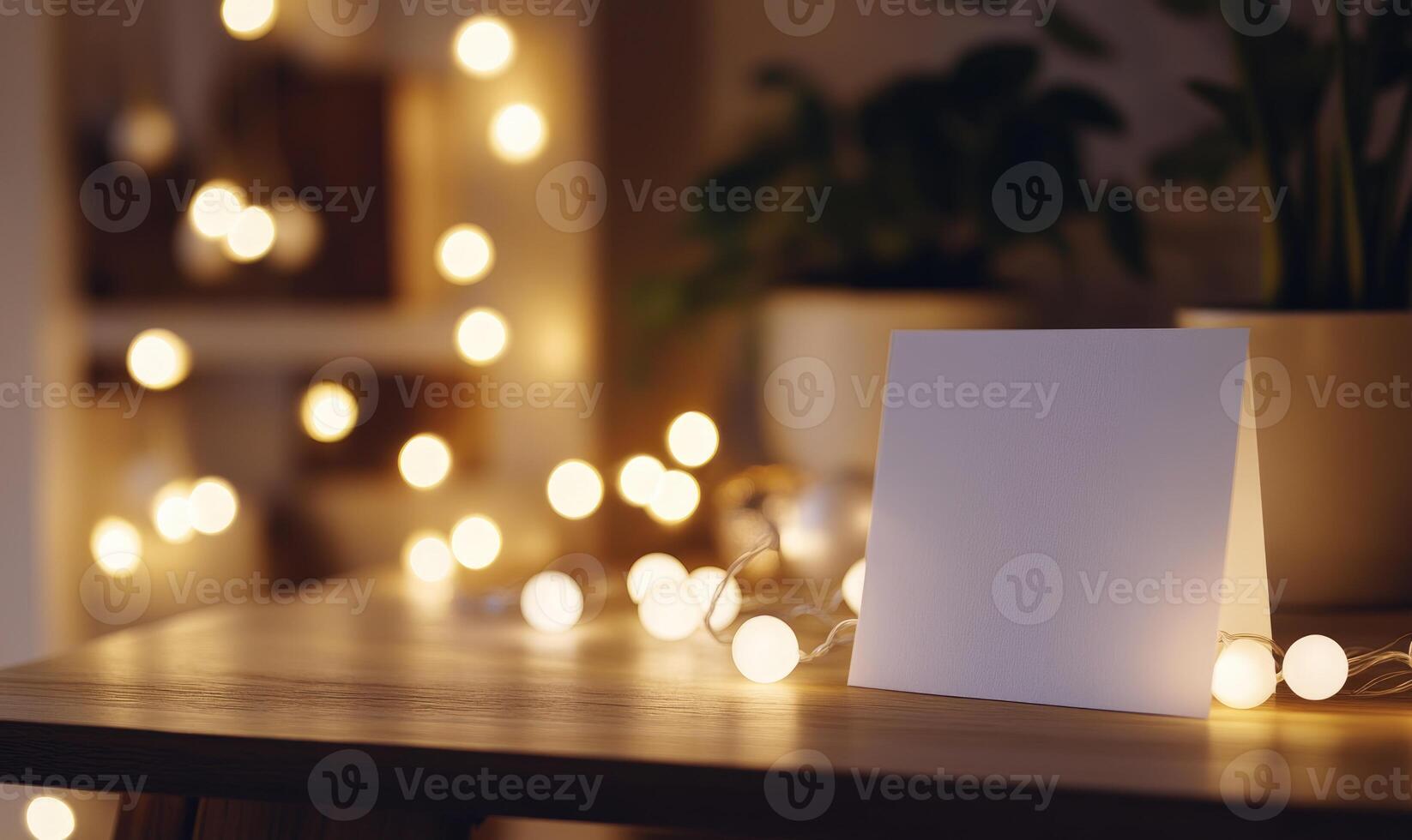 A white card sits on a table in front of a string of lights photo