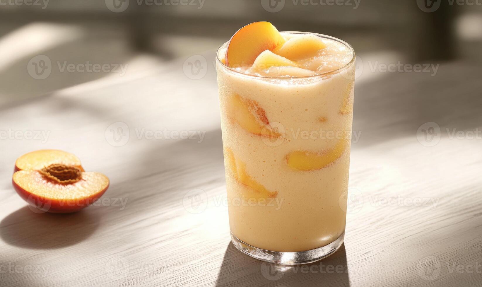 A glass of peach juice is sitting on a table with a peach slice on the side photo