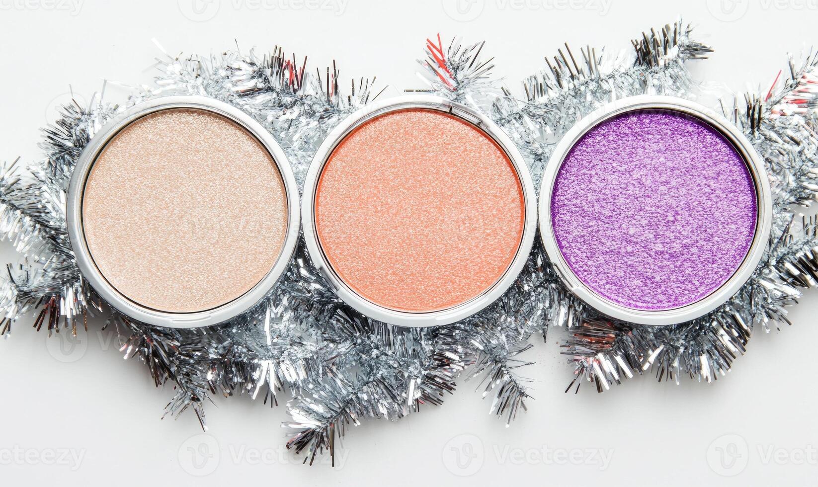 A collection of eyeshadows in soft beige, light blush, peach, and deep violet, decorated with silver tinsel photo