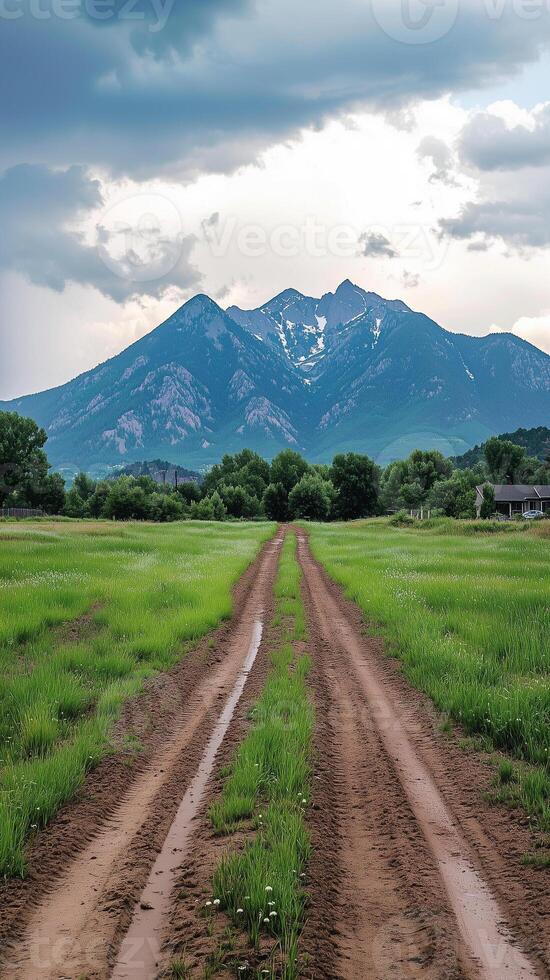 Dirt track crossing field towards mountain silhouette , wallpaper art photo