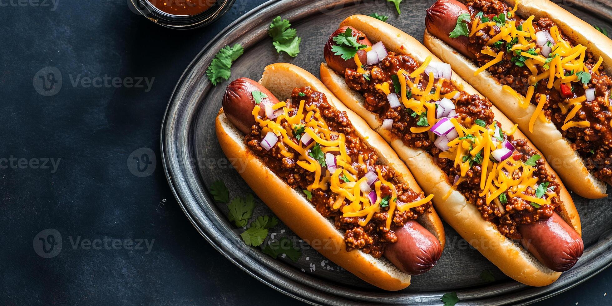 Chili dogs on a metal tray with chili, cheese, and onions, food photography photo