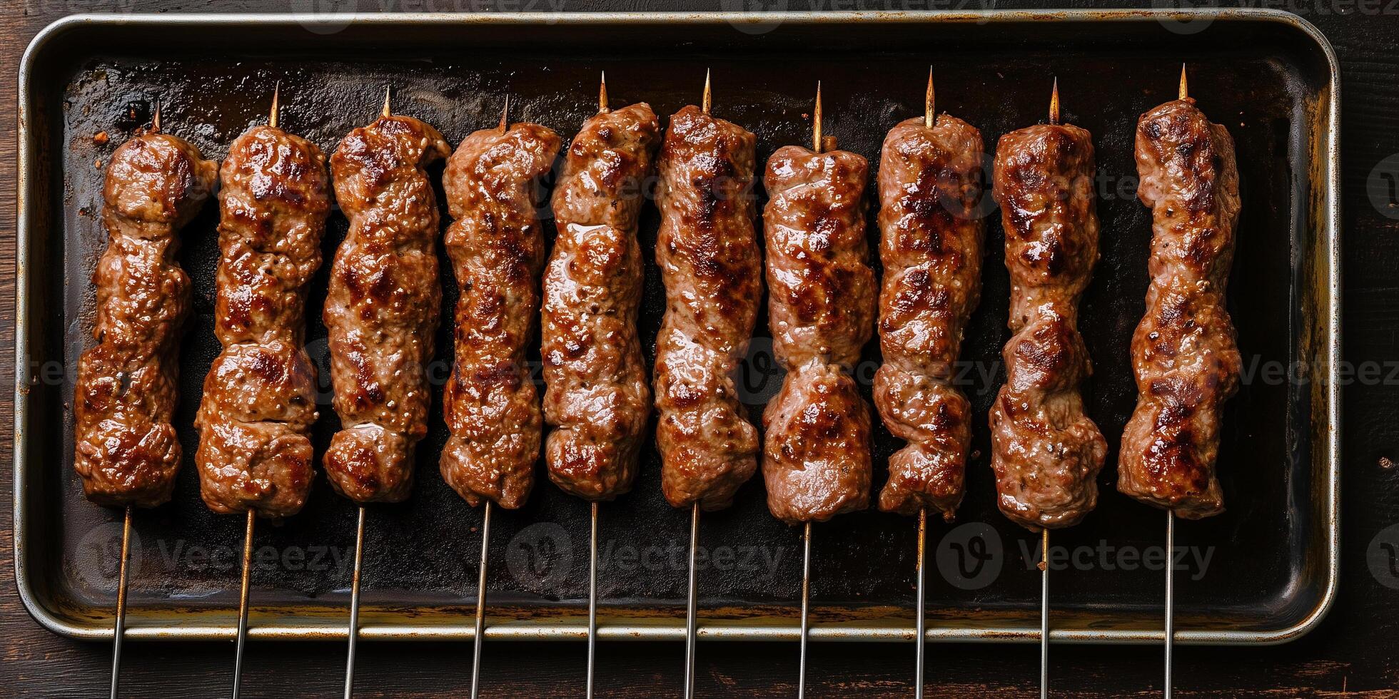 Row of beef kebabs on a metal tray, centered and parallel, meal photography photo