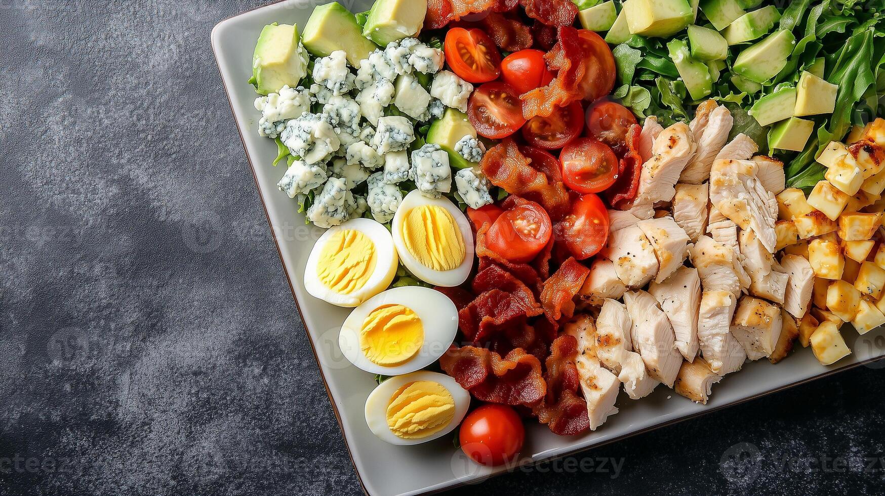 Cobb salad on a square plate with rows of chicken, bacon, eggs, avocado, tomatoes, and blue cheese, meal photography photo