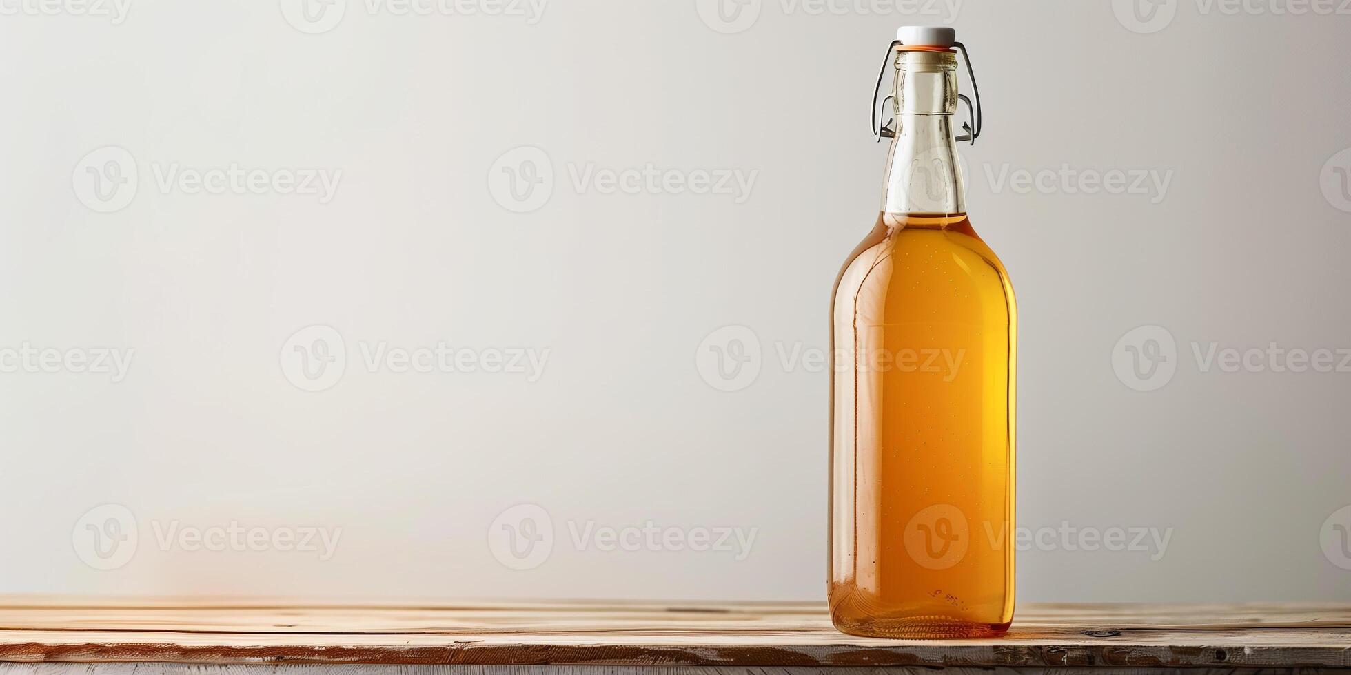 Clear glass bottle containing golden apple cider, displayed on a wooden table against a plain white background, gastronomy photography photo