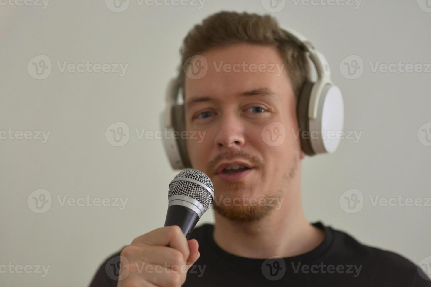 A man wearing headphones speaking preforming a speech in microphone. Blurred image with focus on a hand foreground photo