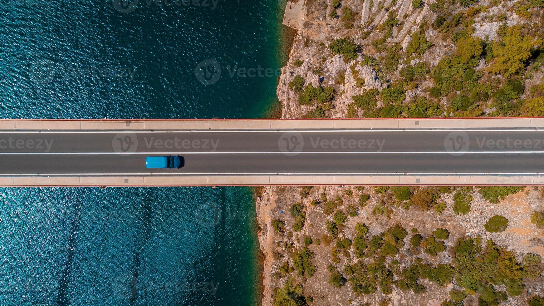 Top down view blue car driving over the bridge over the sea. Background and icon of travel, car journey to discover a country. photo