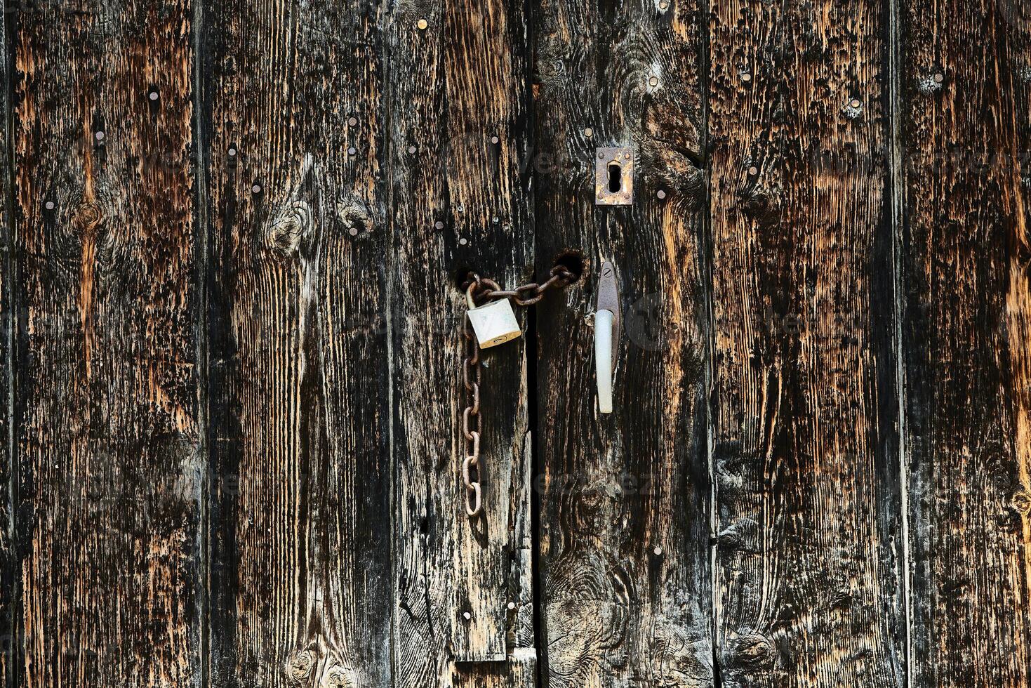 Old wooden door with chain and security lock photo