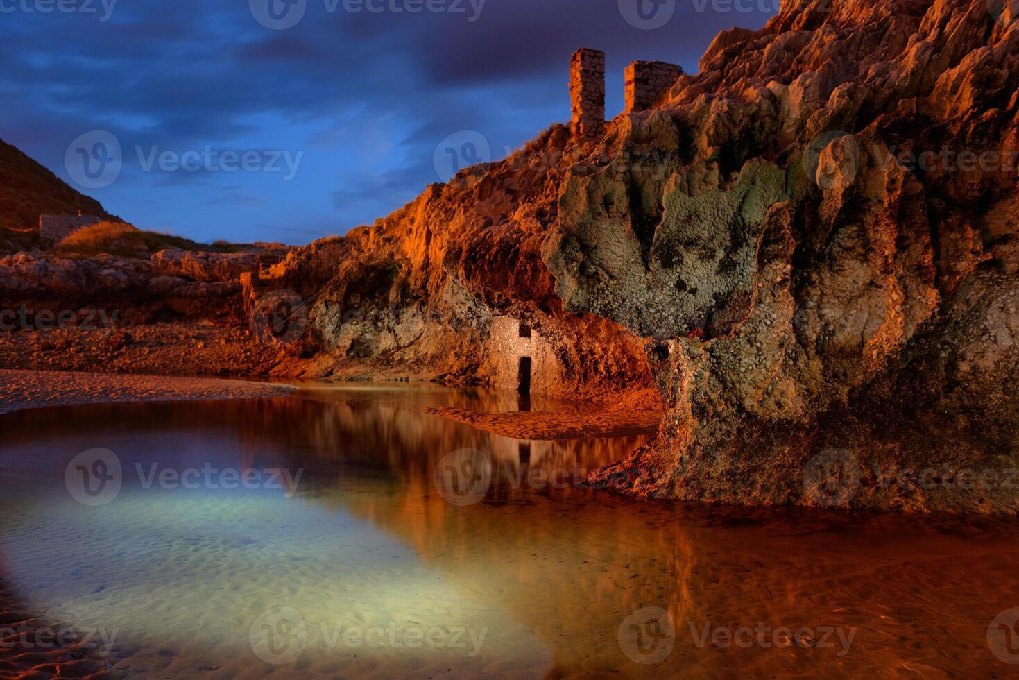 Long exposure of a rock wall with ancient construction in a small lake at dusk with striking color photo