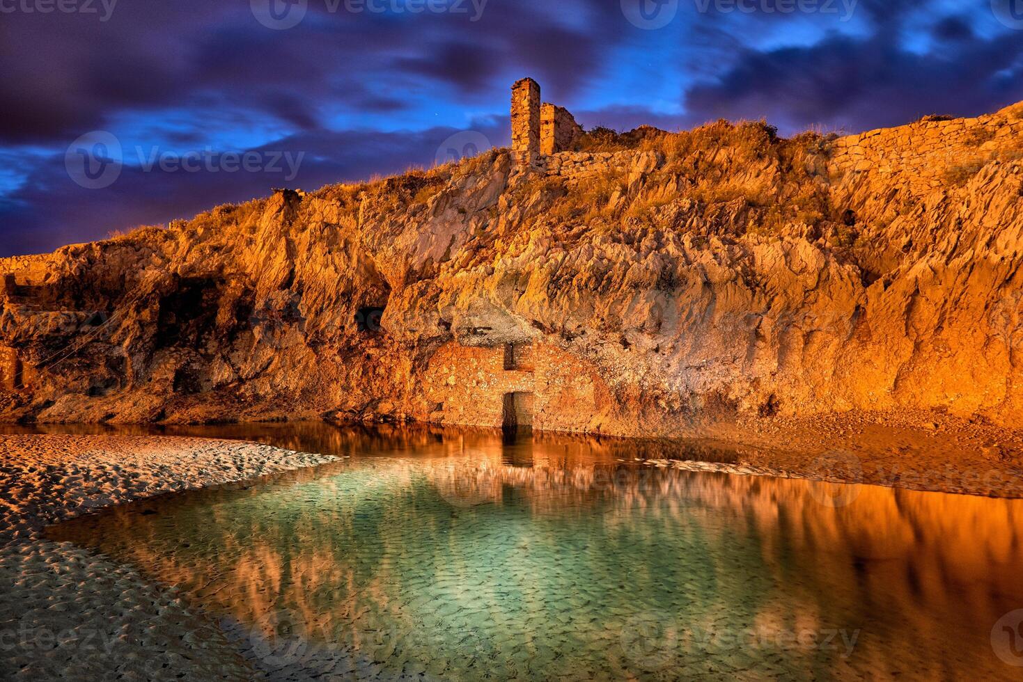 Long exposure of a rock wall with ancient construction in a small lake at dusk with striking color photo