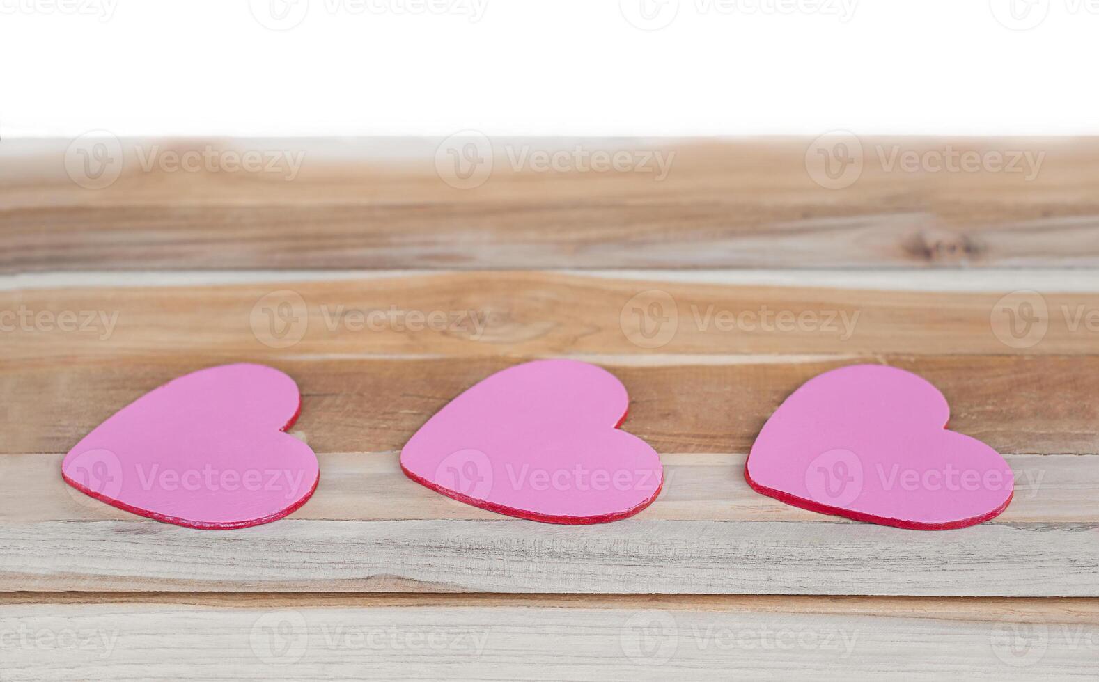 Three hearts on a wooden surface isolated. photo