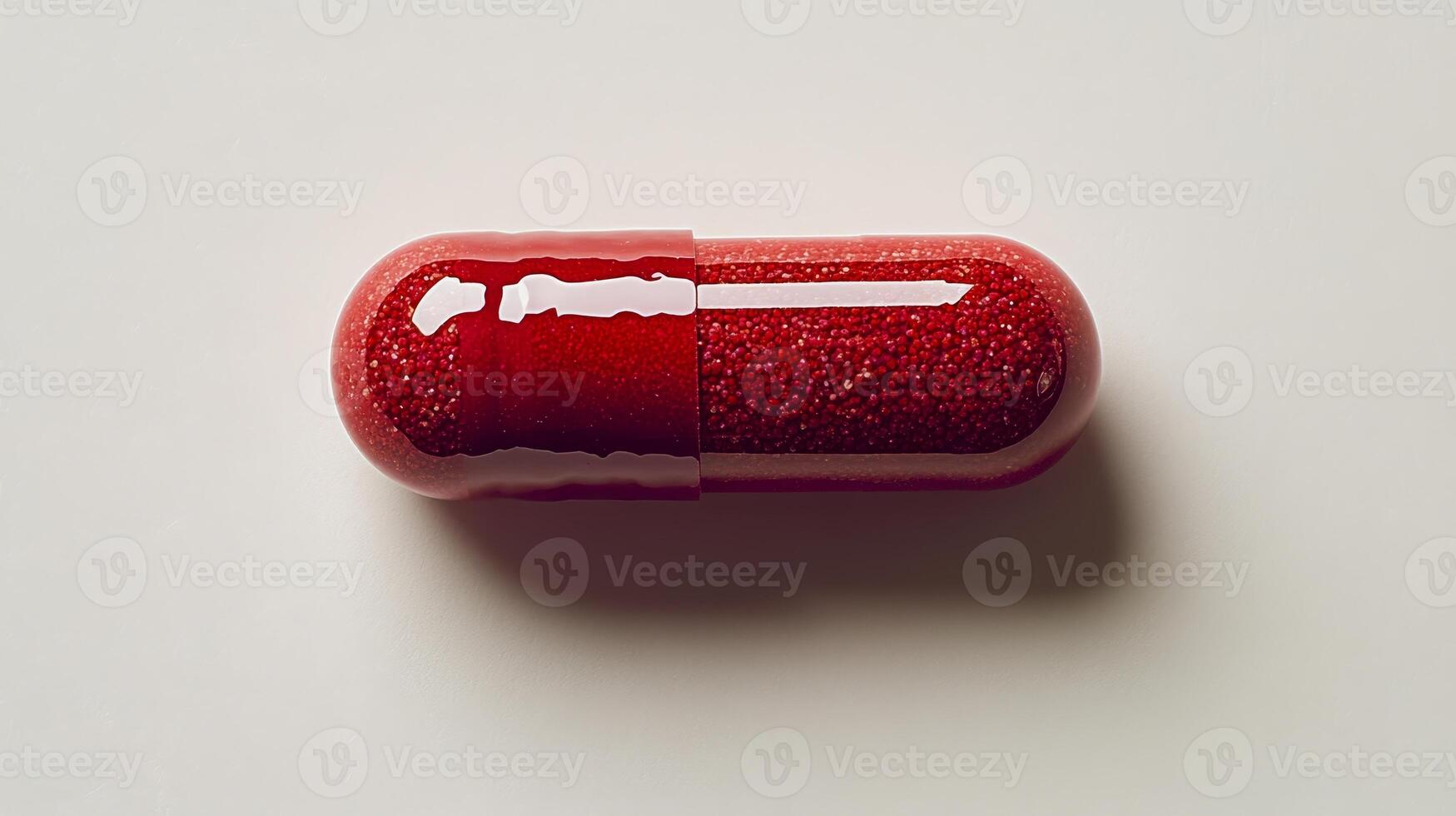 A vibrant red capsule lies on a clean surface, showcasing its bright design and shiny texture photo