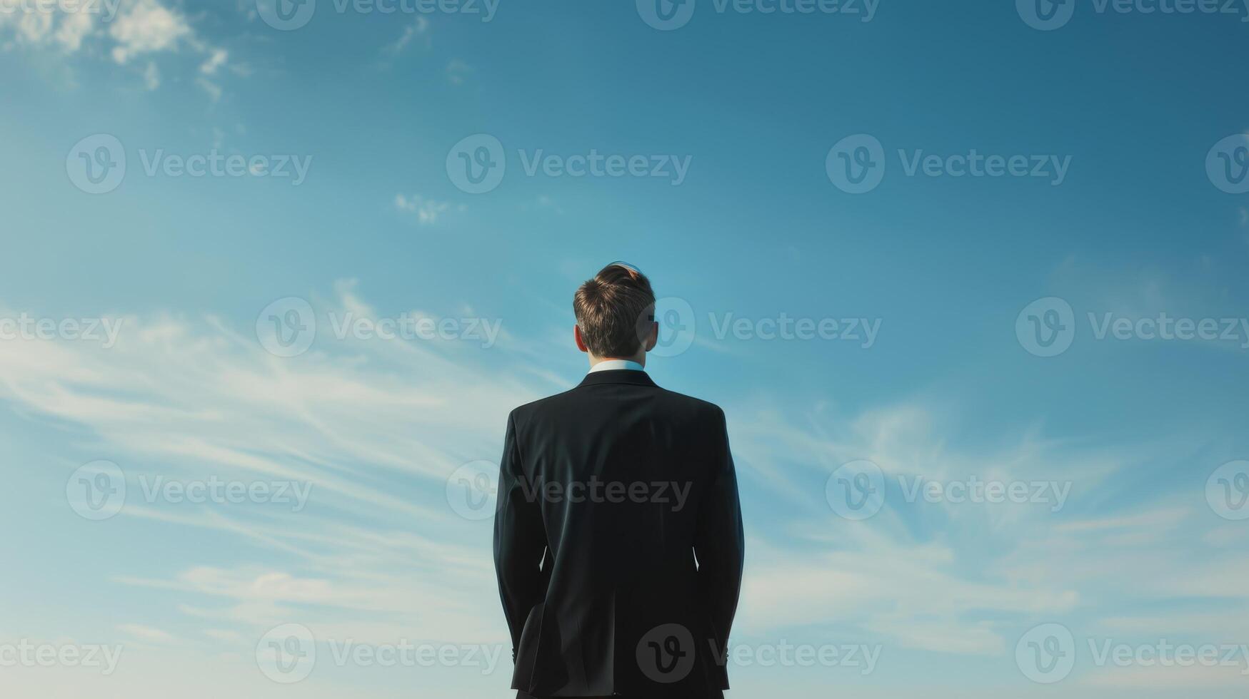 A businessman standing and looking up at the clear blue sky in a minimalist back view stock image photo