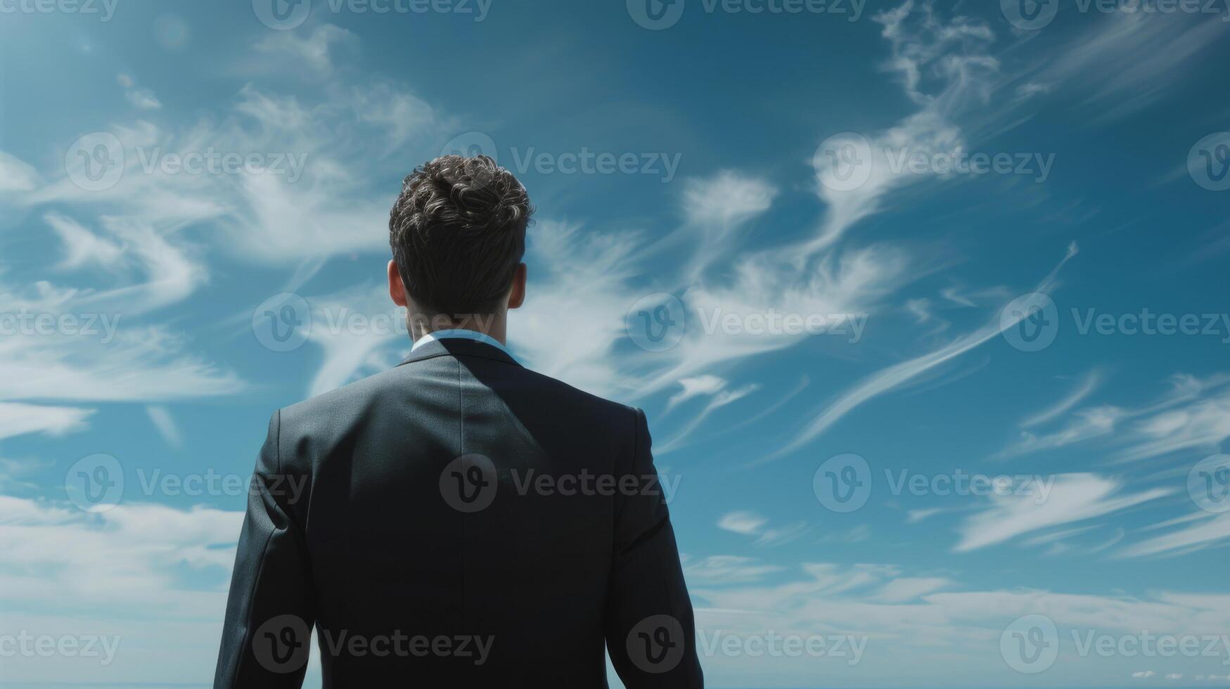 A man in a suit looks at the sky with determination and peace, reflecting on his goals and dreams photo