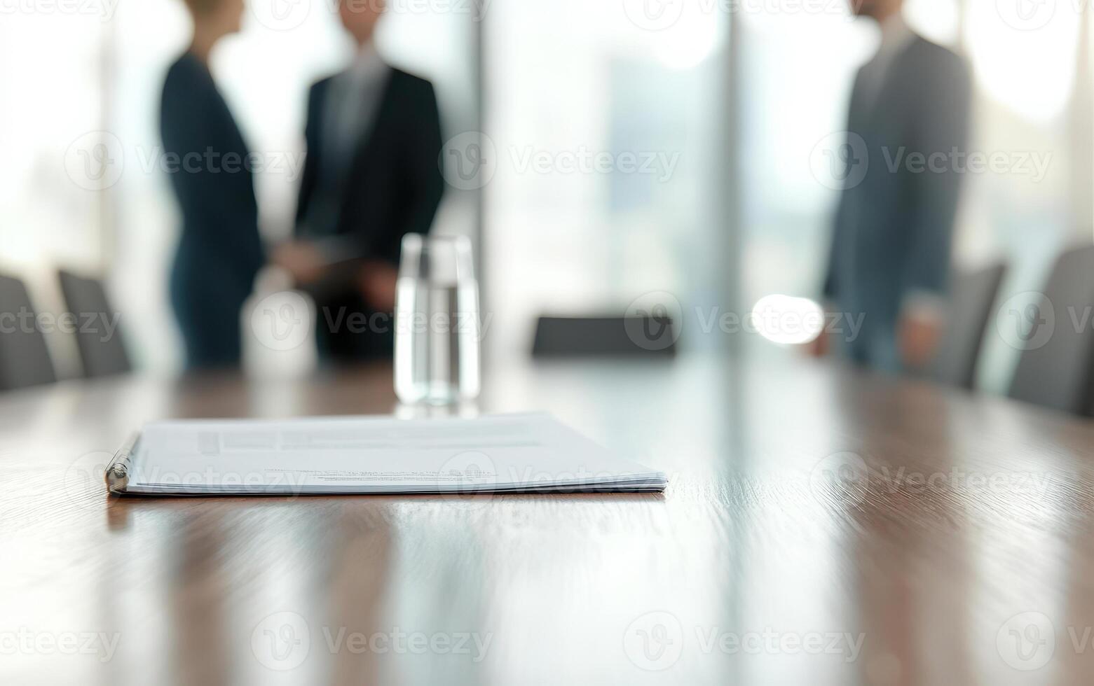 back view of two colleagues discussing report in modern office setting, with focus on document on table and glass of water nearby, creating professional atmosphere photo