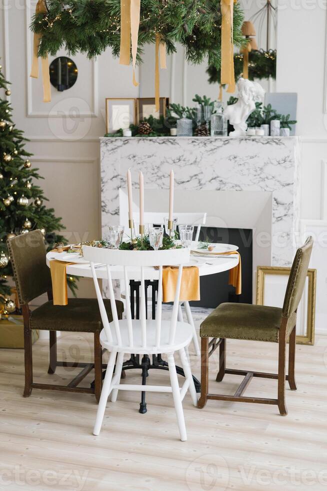 Stylish festive Christmas table with vintage chairs near the marble fireplace and Christmas tree in the living room or dining room in the house photo