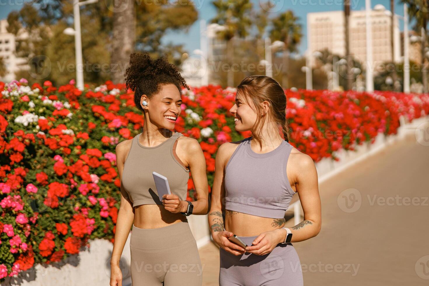 Two young female sportswomen have a rest after morning jogging outdoors and looks each other photo