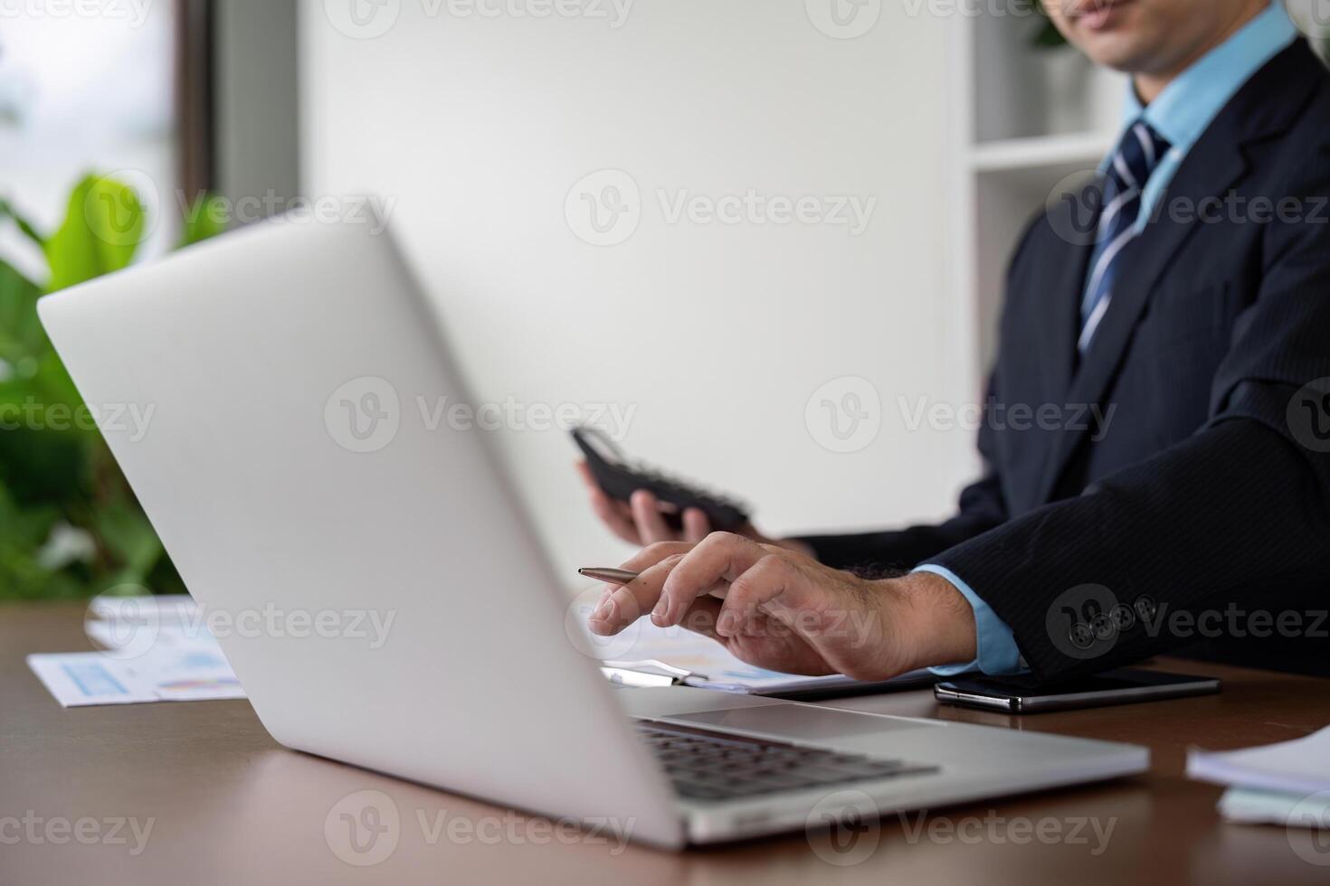 Businessman Working on Laptop with Calculator and Notes photo