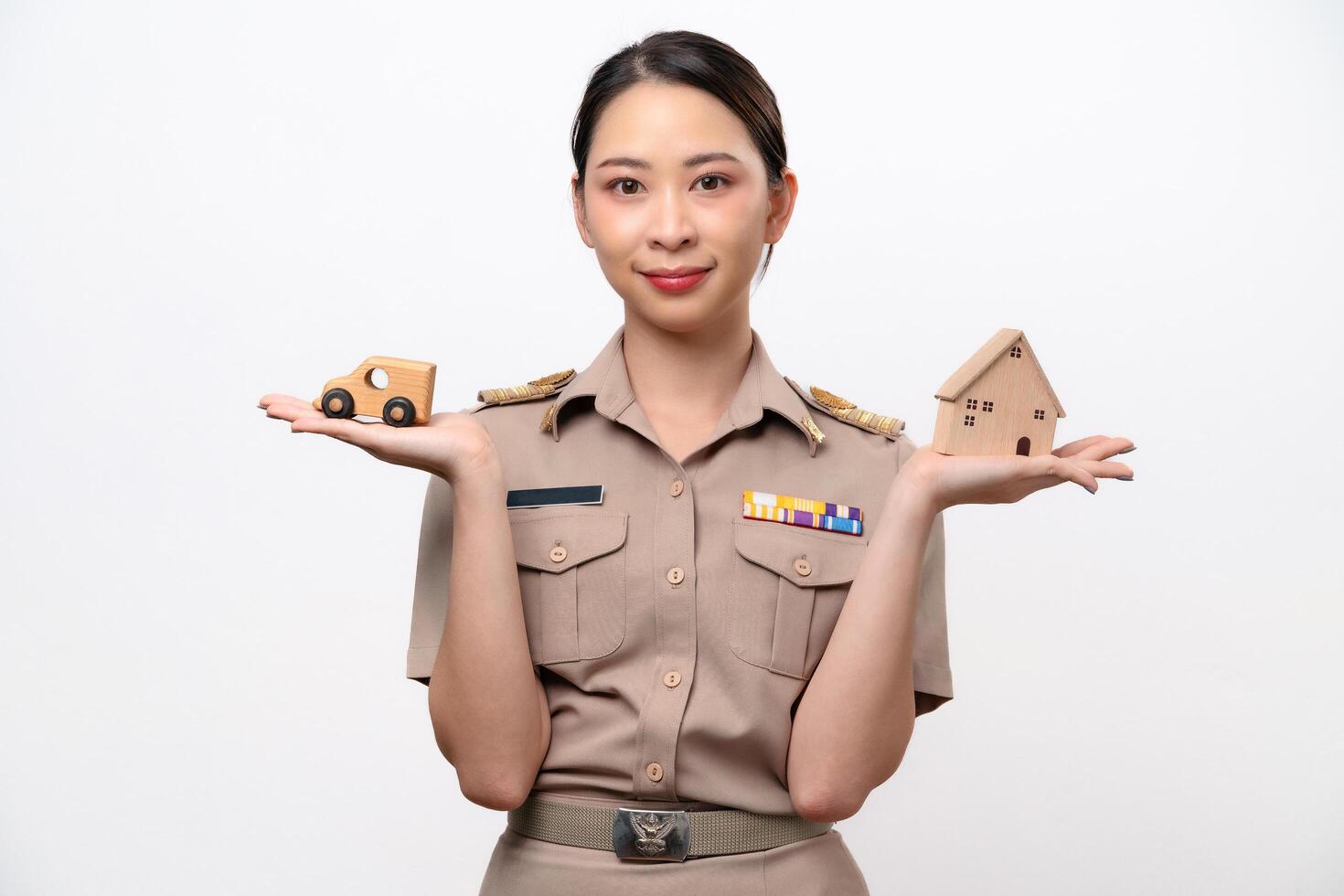 Young Thai Asian Teacher in the uniform is holding wooden house and car toy photo