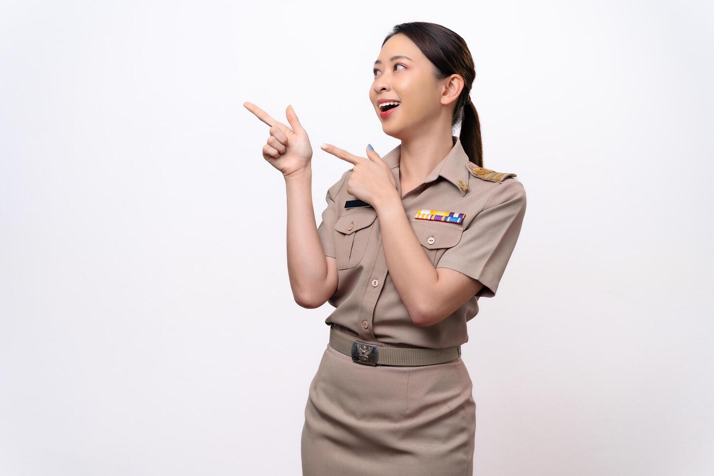 Young Thai Asian Teacher in the uniform is pointing to the empty copy space. photo