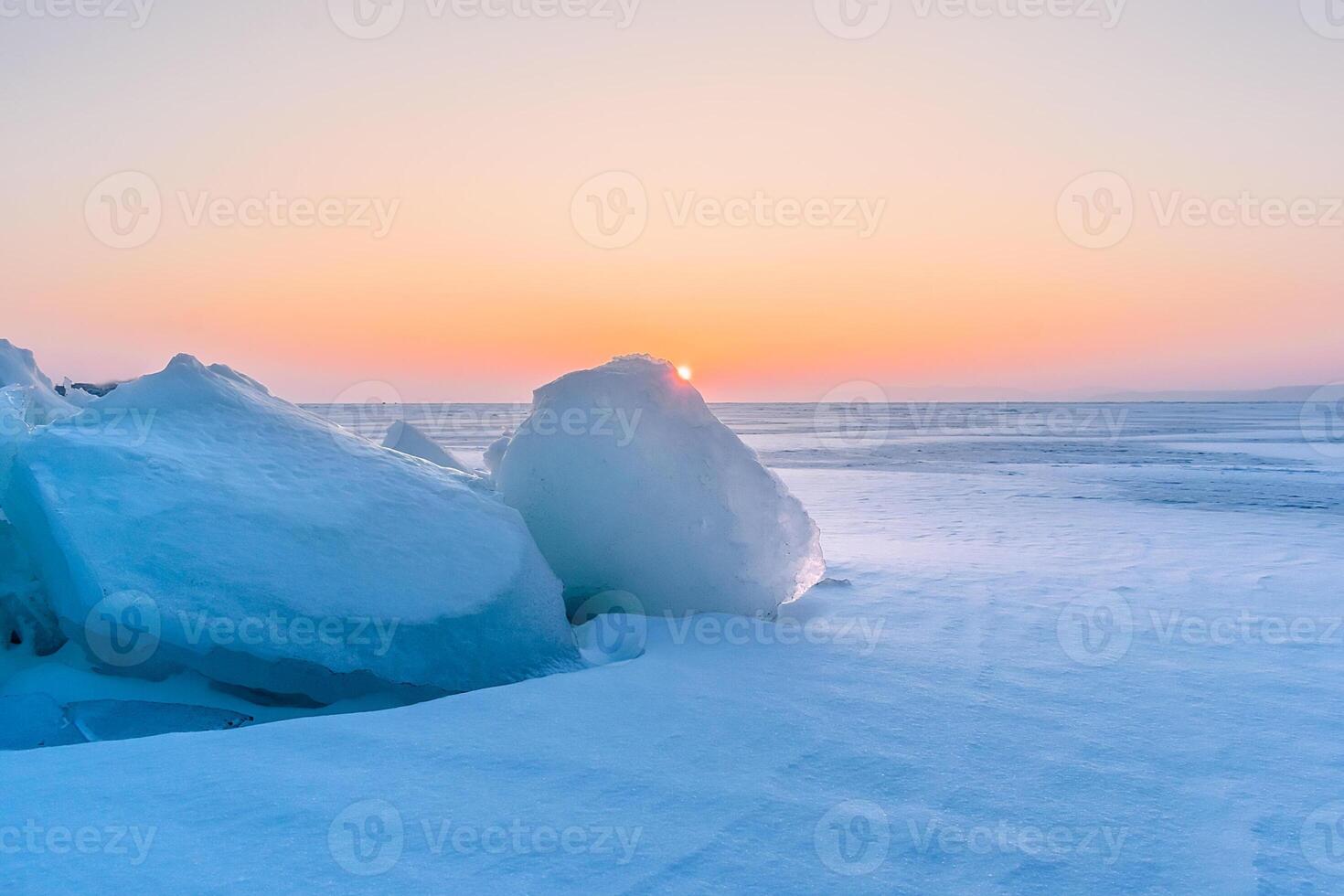 Winter landscape. A frozen surface of ice with snow intersected by many cracks. photo
