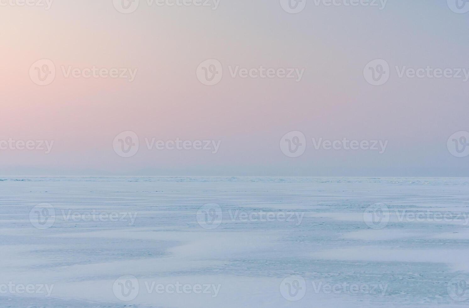 Winter landscape. A frozen surface of ice with snow intersected by many cracks. photo