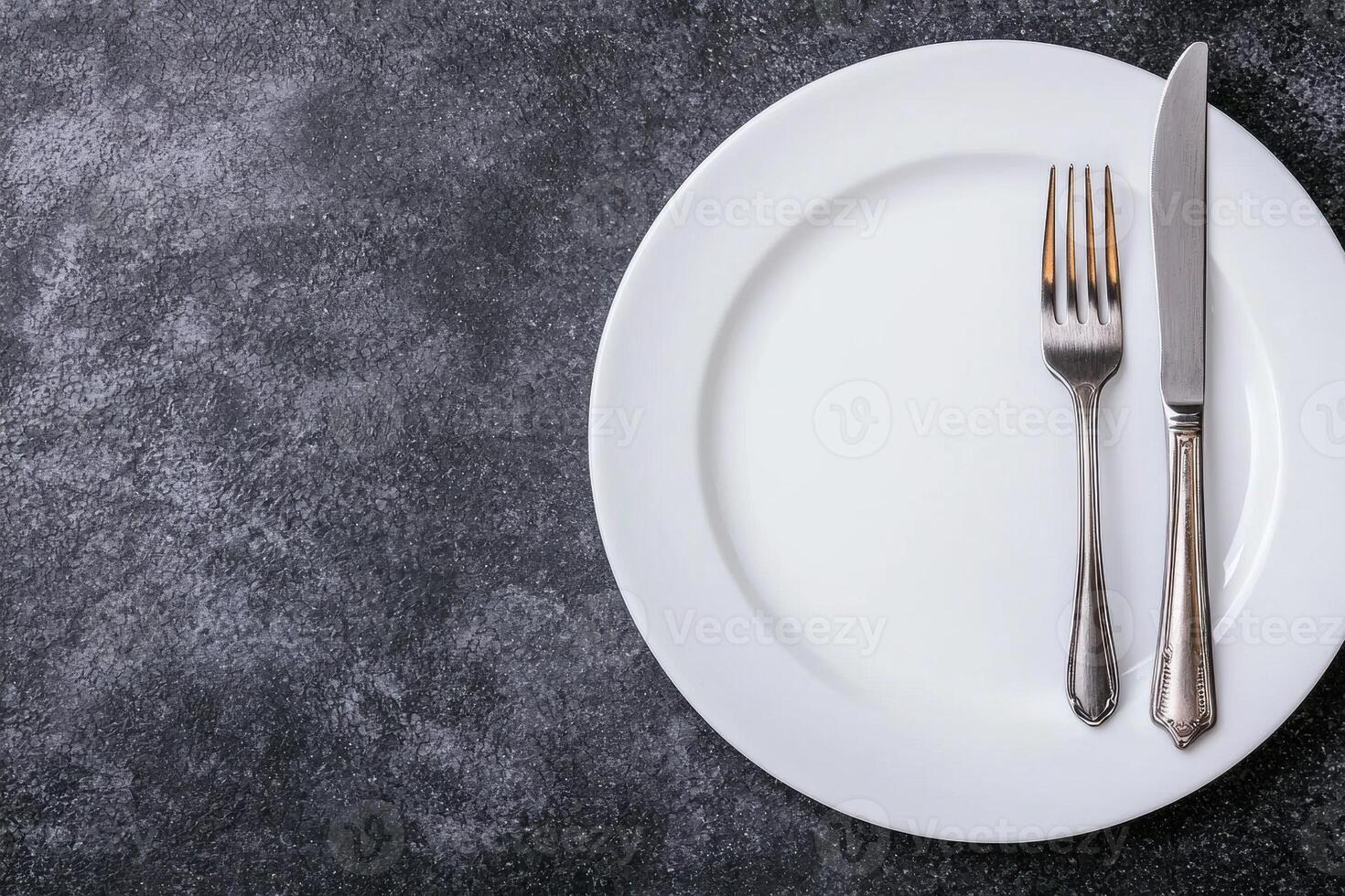 Empty white plate with silverware on dark background photo