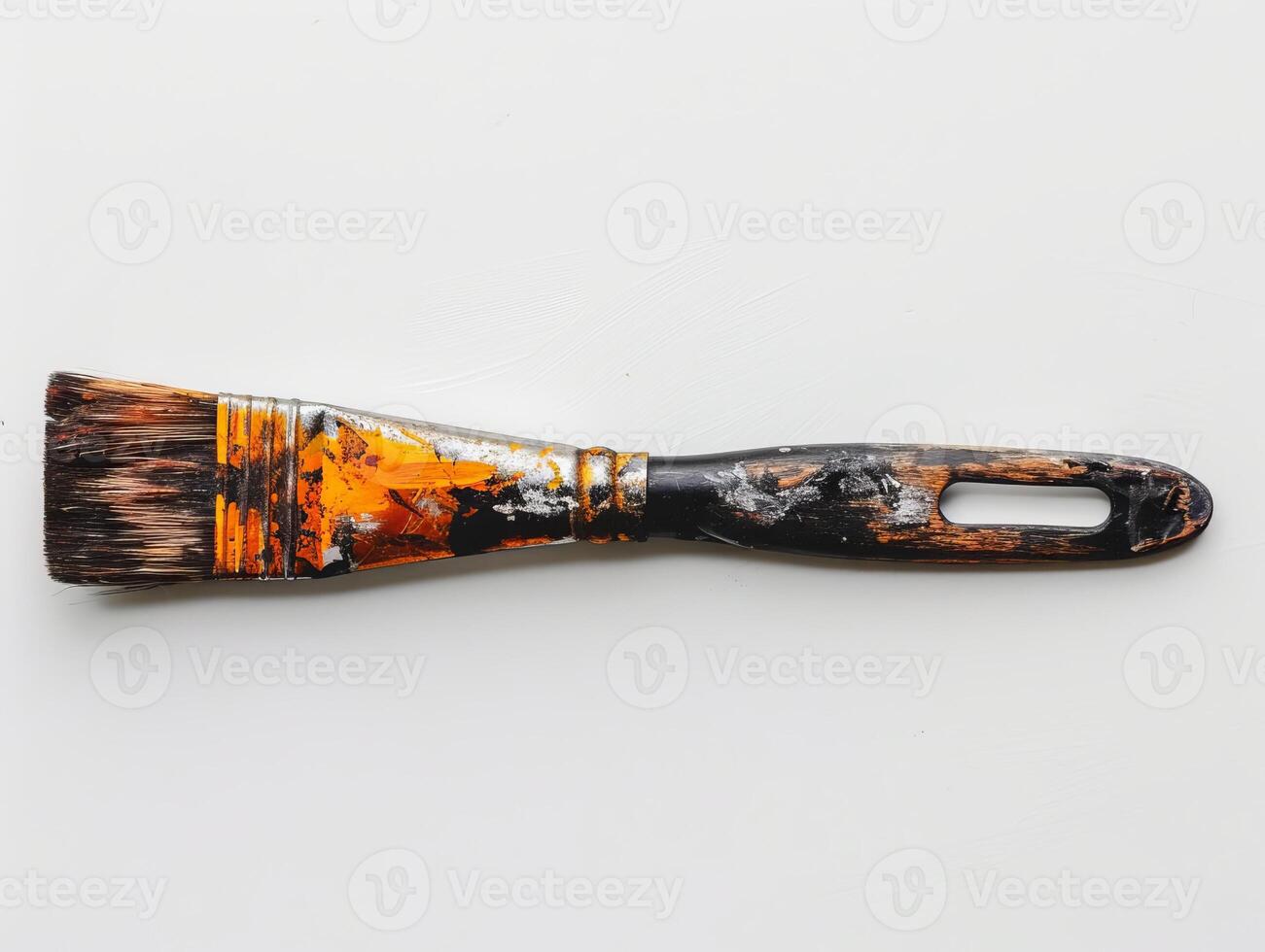 Weathered paint brush with vibrant orange and black splatter photo