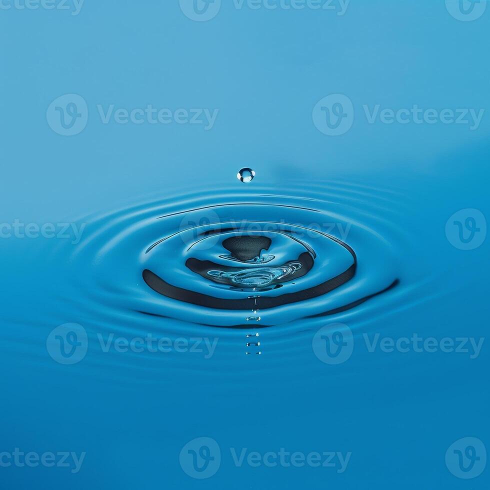 Perfect water droplet creating ripples on serene blue surface photo