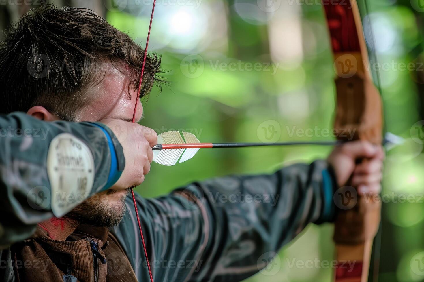Focused archer aiming with a bow in a forest photo
