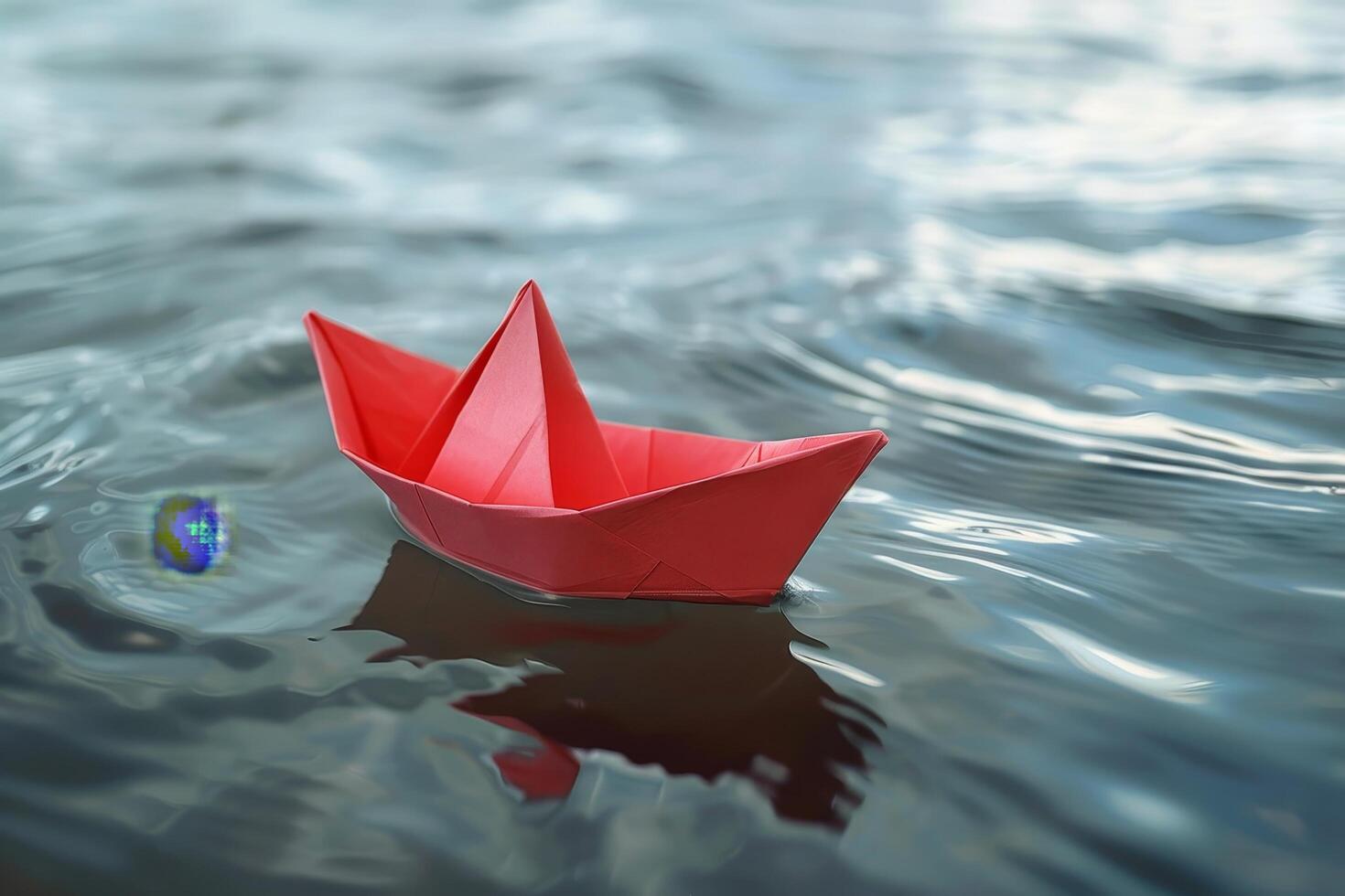 Red paper boat floating on tranquil water photo
