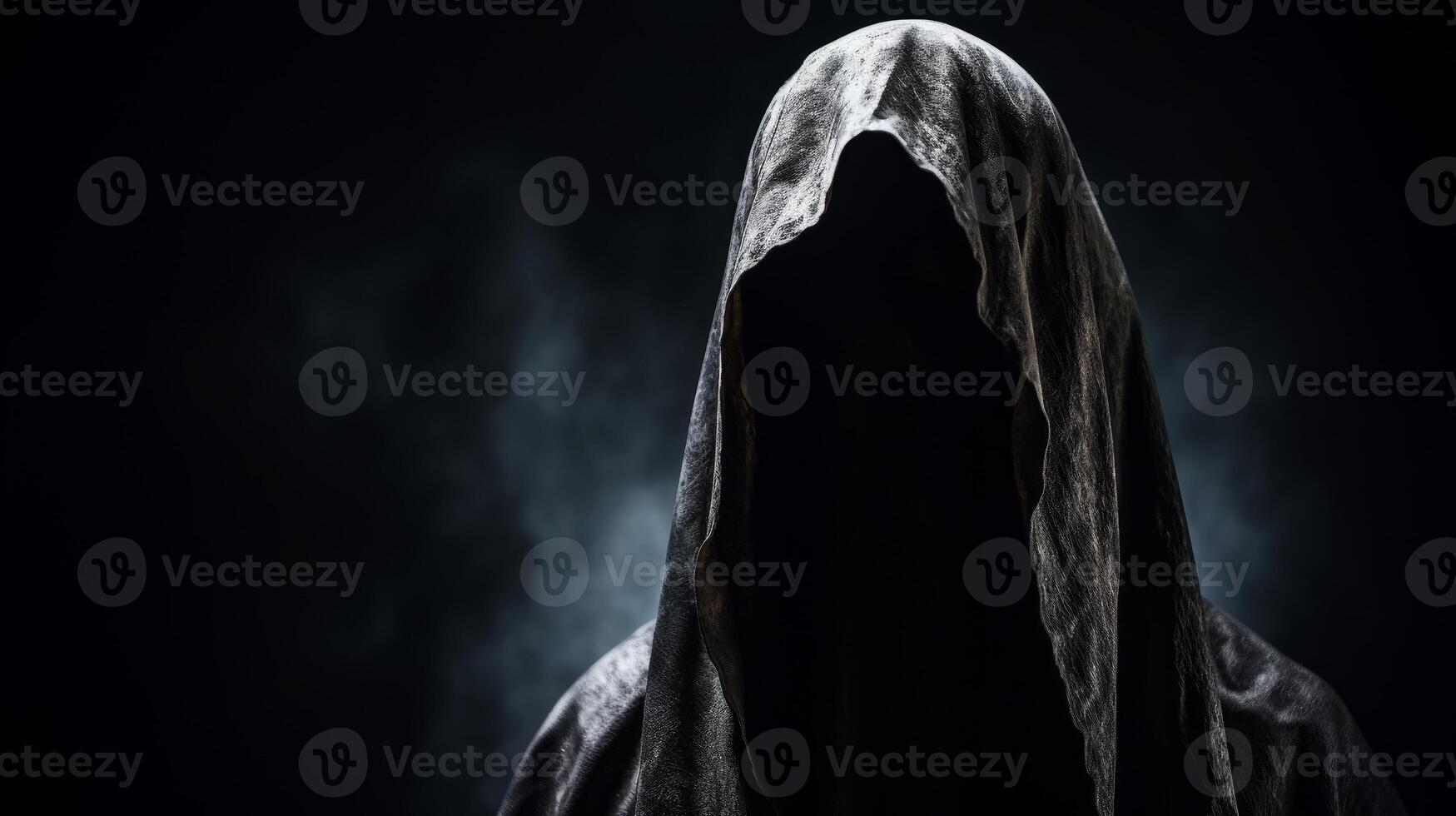 Mysterious figure shrouded in a hood against a dark background photo