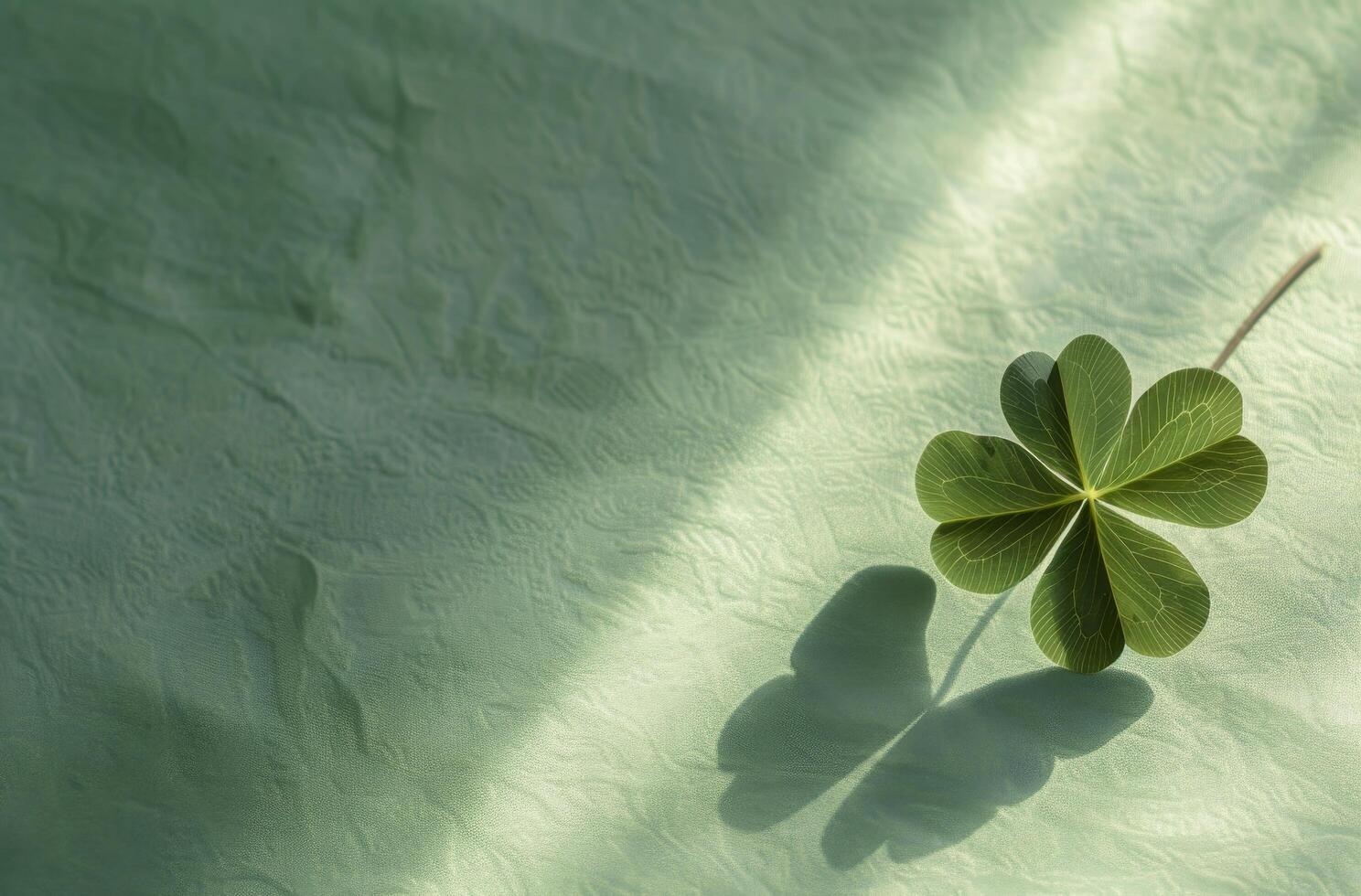 Four leaf clover casting a shadow on a textured green surface photo