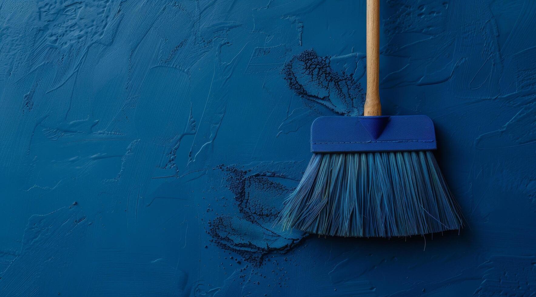 Broom sweeping dust on a textured blue surface photo