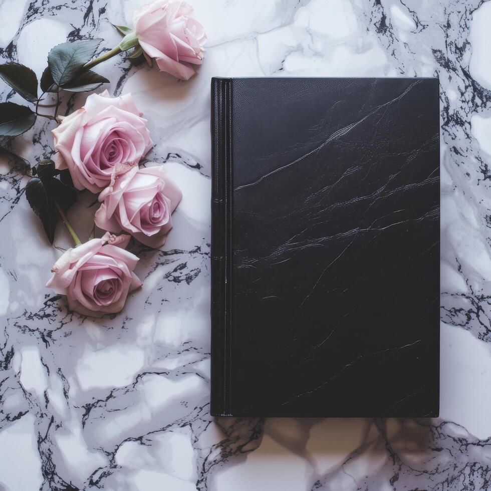 Elegant black notebook with pink roses on a marble background photo