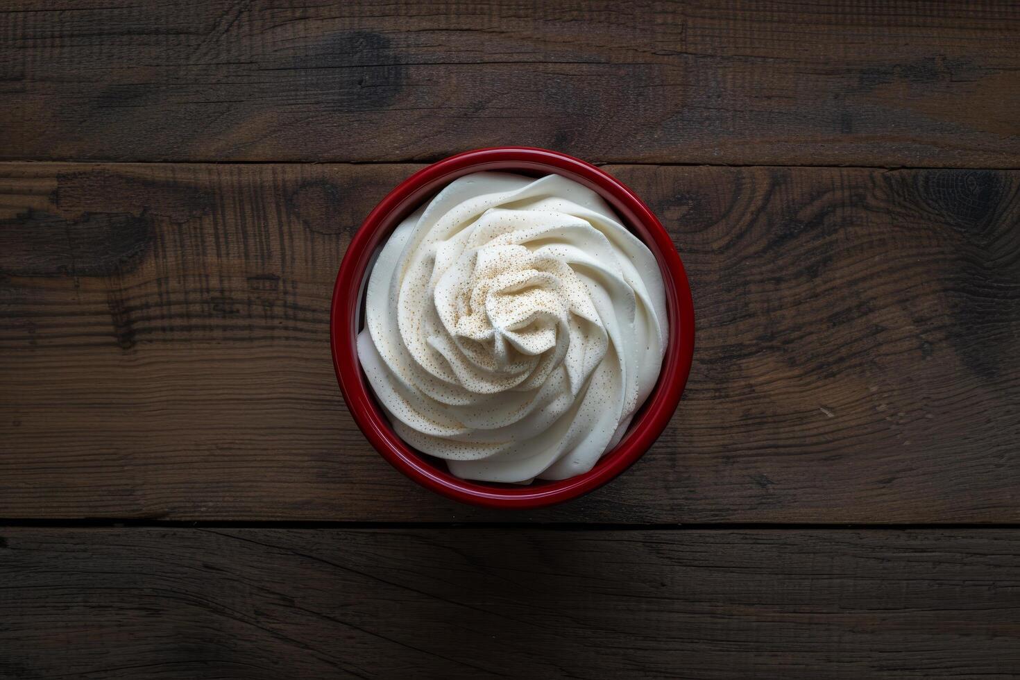 Soft serve ice cream in a red bowl on a wooden table photo