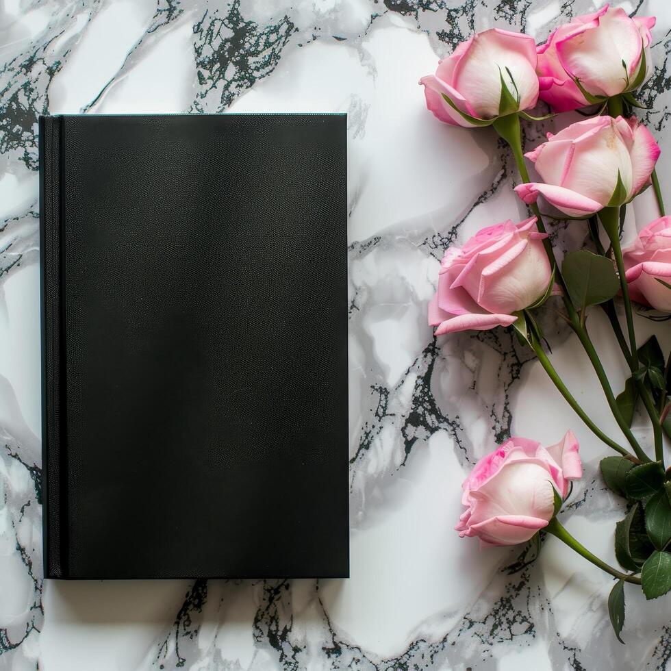 Black notebook with pink roses on marble background photo