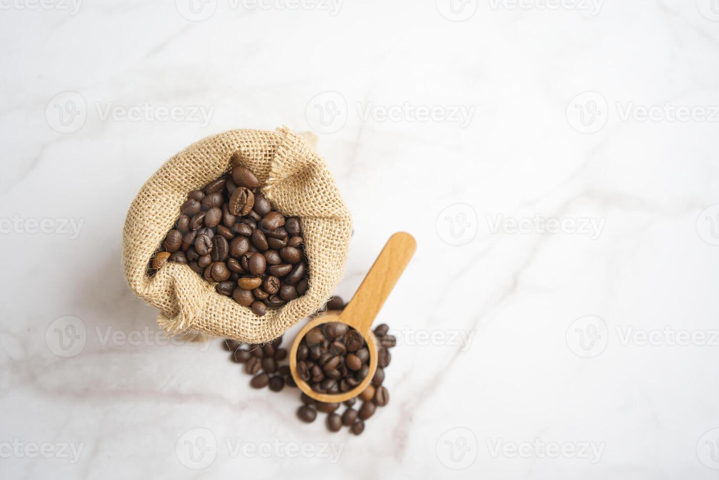 Coffee beans in a wooden spoon with a bag of coffee beans on White Background photo