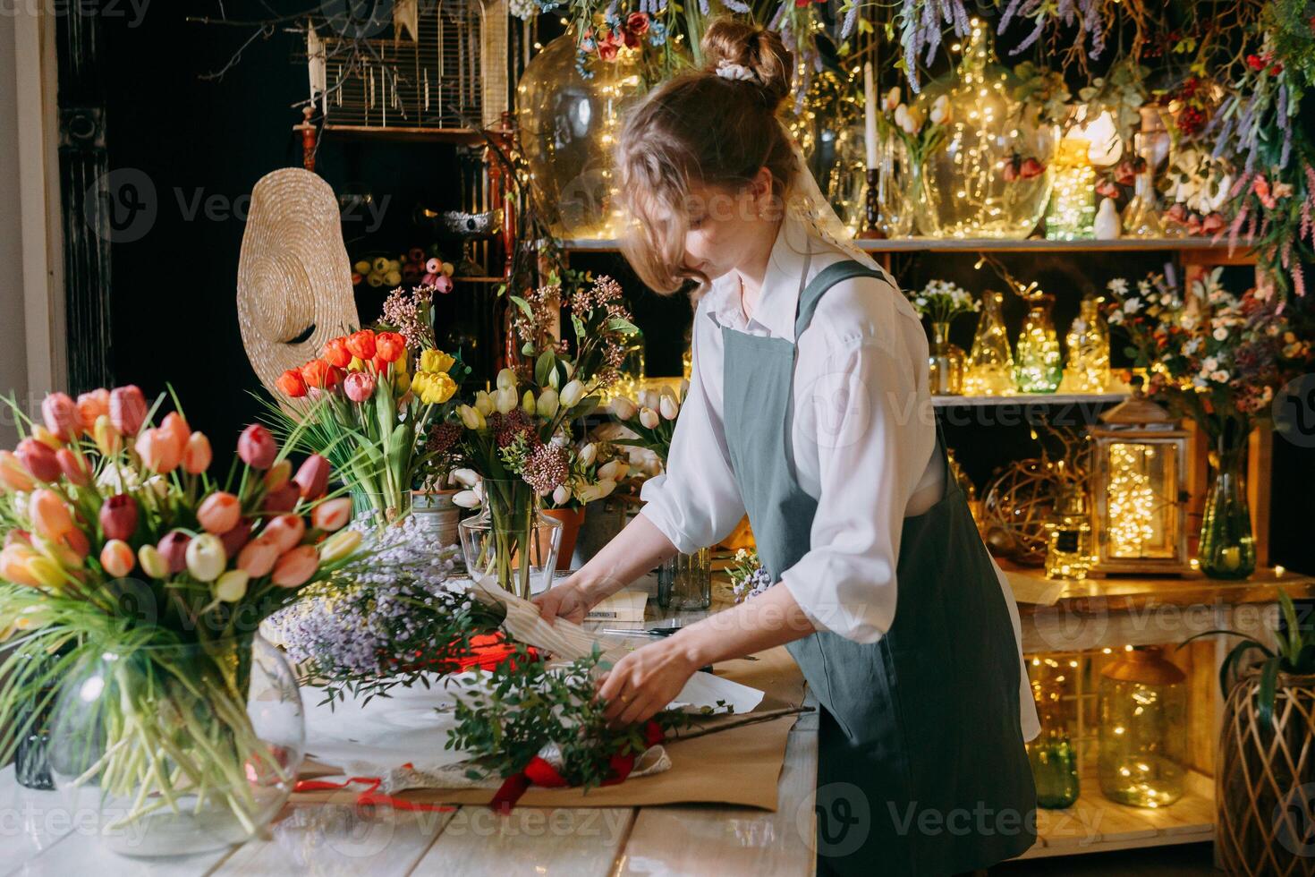 A woman in her florist shop collects bouquets of flowers. The concept of a small business. Bouquets of tulips for the holiday on March 8. photo
