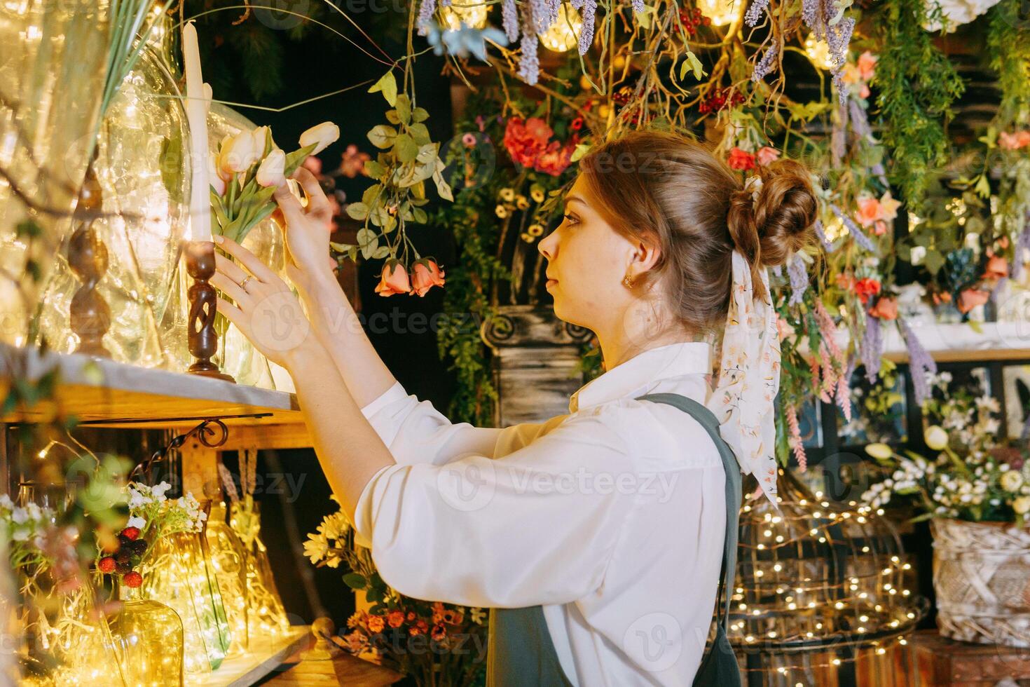 A woman in her florist shop collects bouquets of flowers. The concept of a small business. Bouquets of tulips for the holiday on March 8. photo