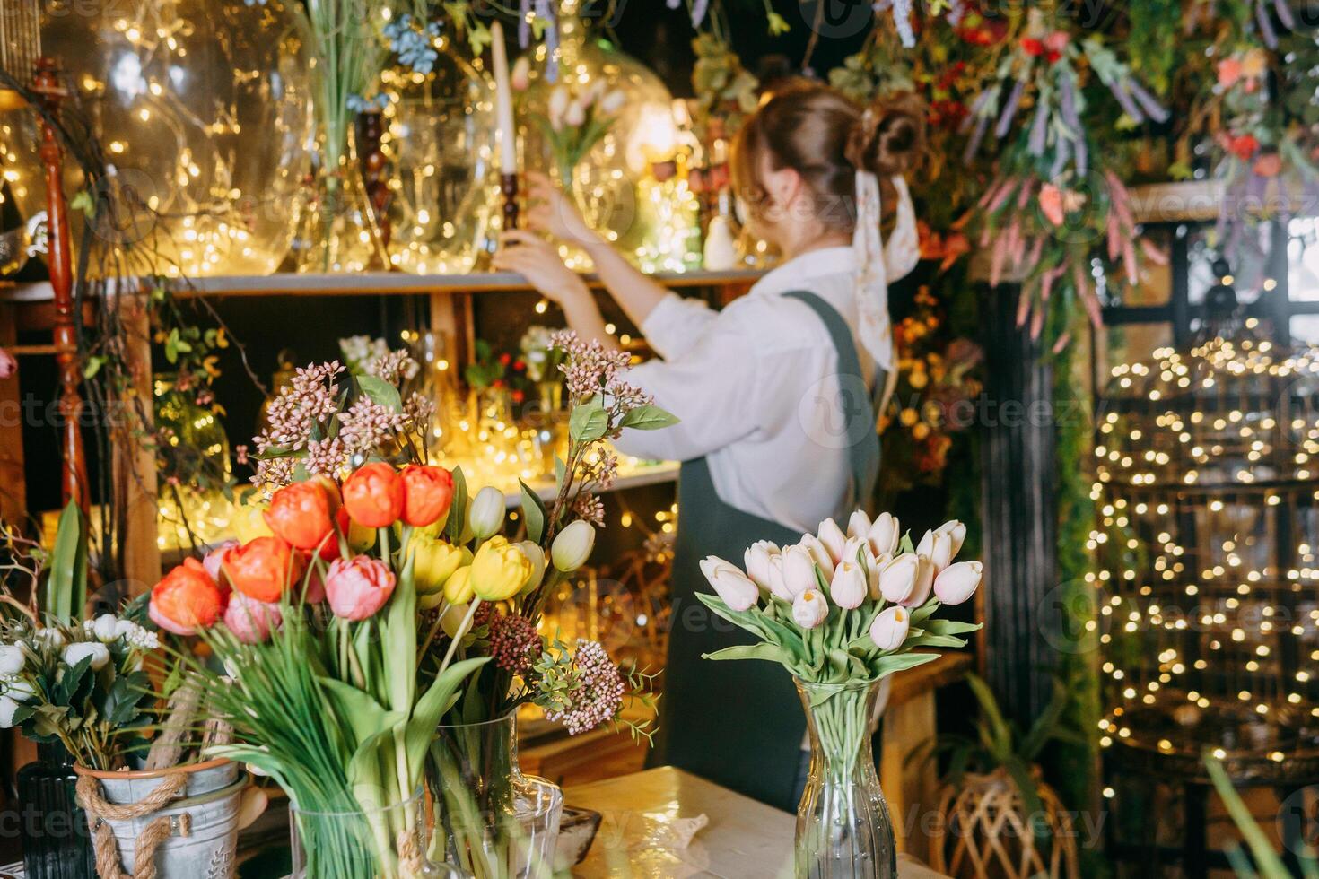 A woman in her florist shop collects bouquets of flowers. The concept of a small business. Bouquets of tulips for the holiday on March 8. photo