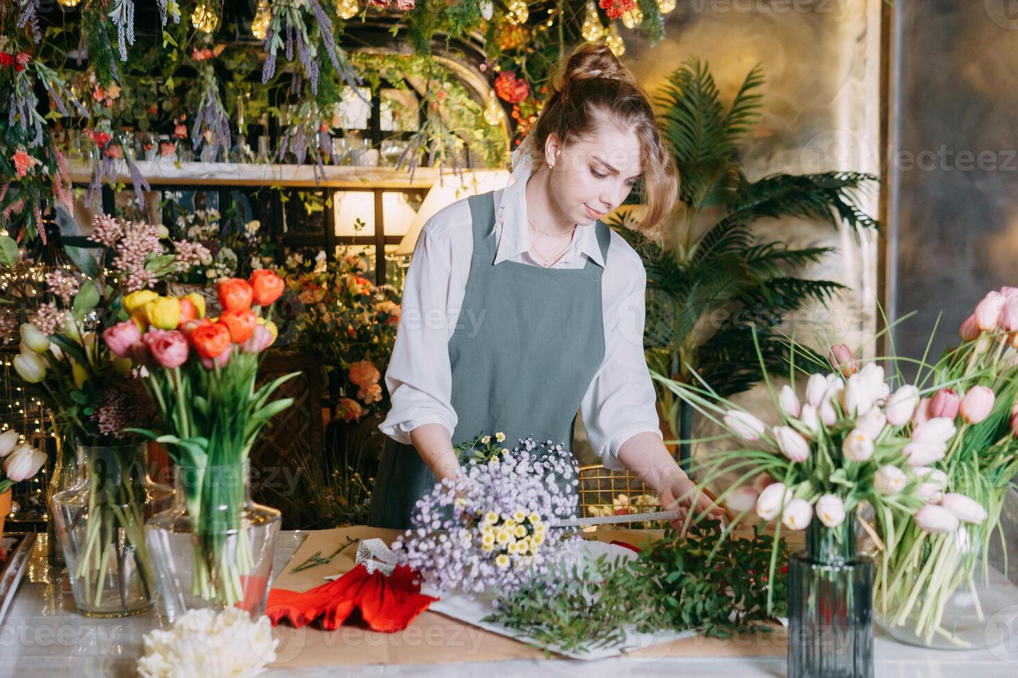 A woman in her florist shop collects bouquets of flowers. The concept of a small business. Bouquets of tulips for the holiday on March 8. photo