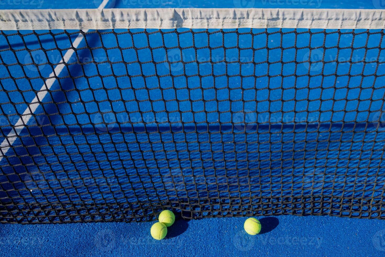 detailed close-up of paddle tennis balls resting at the net on court photo
