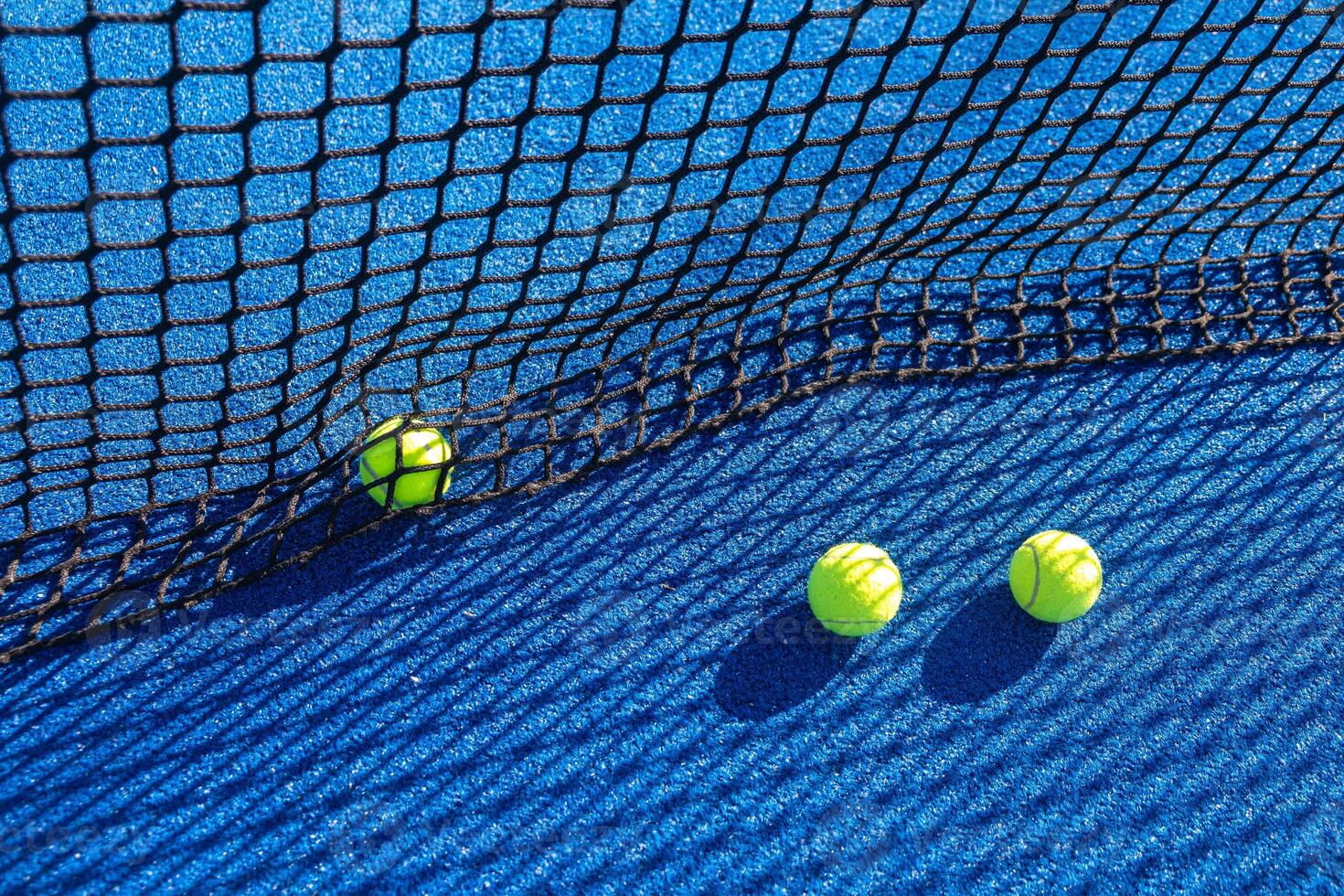 multiple paddle tennis balls lying close to the net on the court photo