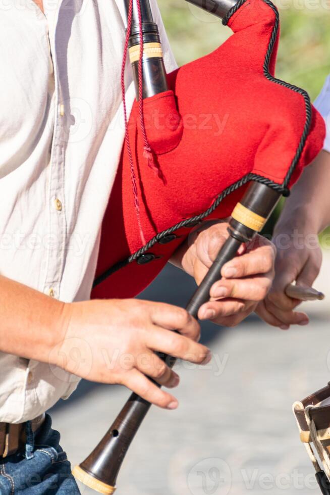detail of the hands of a bagpipe player playing a traditional red bagpipe from Portugal, background concept folk music photo