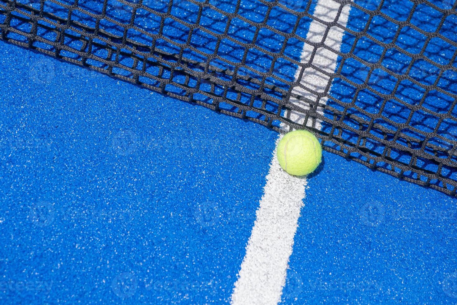a ball at the foot of the net of a paddle tennis court with the background out of focus, a racket sport background concept photo
