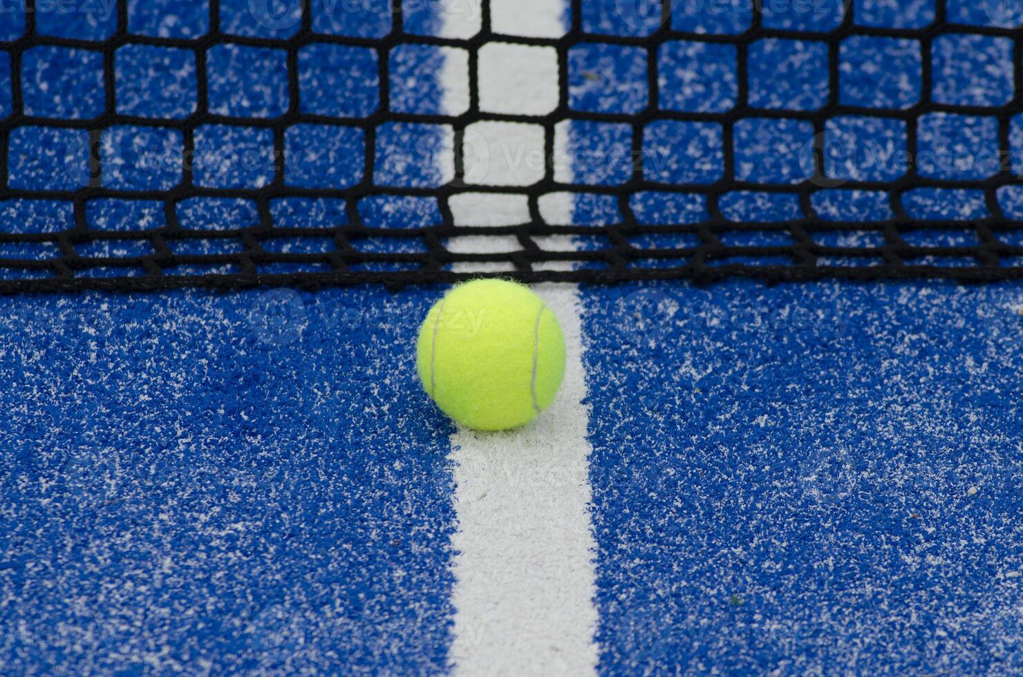 blue paddle tennis court and net with a ball, racket sports concept photo